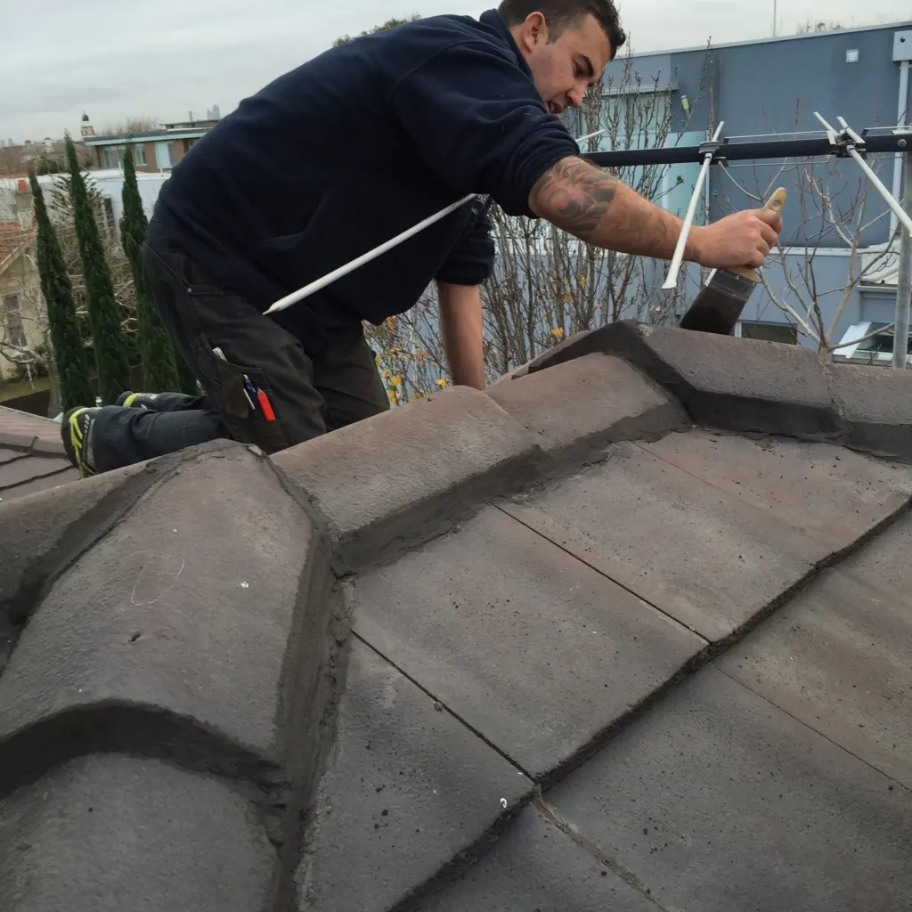 A Mr Roofing tradesman repointing the ridge capping on a tiled roof.